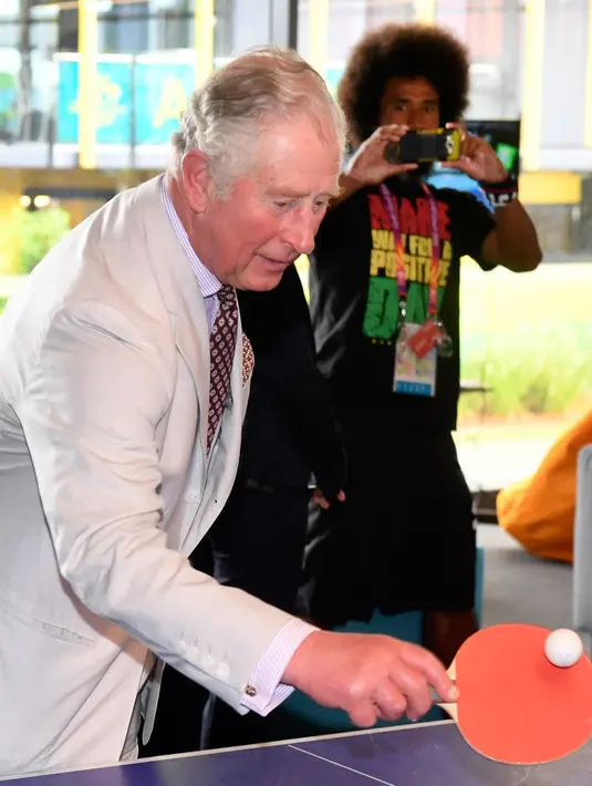 Pangeran Charles memukul bola saat bermain tenis meja selama kunjungannya ke desa atlet Goldwe Common Games 2018 di Gold Coast (5/4). Dalam kunjungannya Pangeran Charles ditemani sang istri Camilla Parker. (AFP Photo/Pool/William West)