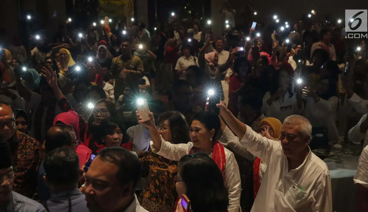 Relawan Jokowi Bersatu menyalakan lampu telfon genggam saat bernyanyi bersama pada Halal bi Halal Relawan Jokowi Bersatu di Jakarta, Jumat (5/7/2019). Acara tersebut dihadiri ratusan relawan yang tergabung dalam 16 kelompok pendukung Jokowi-Ma’ruf Amin. (Liputan6.com/Helmi Fithriansyah)