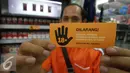 Seorang lelaki menunjukkan stiker larangan menjual rokok kepada anak di bawah usia 18 tahun, Jakarta, Rabu (30/11). Sampoerna memperkuat komitmen untuk mencegah akses penjualan rokok kepada anak-anak (Liputan6.com/Ferry Pradolo)