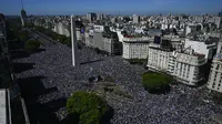 Pendukung Argentina menunggu bus yang membawa Lionel Messi dan kawan-kawan pada parade juara Piala Dunia 2022 di Obelisk Buenos Aires, Selasa (20/11/2022). (AFP/Luis Robayo)