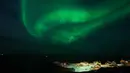 Fenomena ini juga hanya bisa dilihat di lokasi dan pada waktu tertentu. Tampak dalam foto, Aurora Borealis menerangi langit malam di atas rumah-rumah penduduk di Nuuk, Greenland, pada 23 Januari 2026. (Jonathan NACKSTRAND/AFP)
