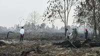 Presiden Joko Widodo atau Jokowi (kiri) melihat pemadam kebakaran bekerja saat memeriksa kerusakan akibat kebakaran hutan dan lahan (karhutla) di Pekanbaru, Riau, Selasa (17/9/2019). Jokowi ditemani sejumlah pejabat saat meninjau lokasi kebakaran. (Handout/Indonesian Presidential Palace/AFP)