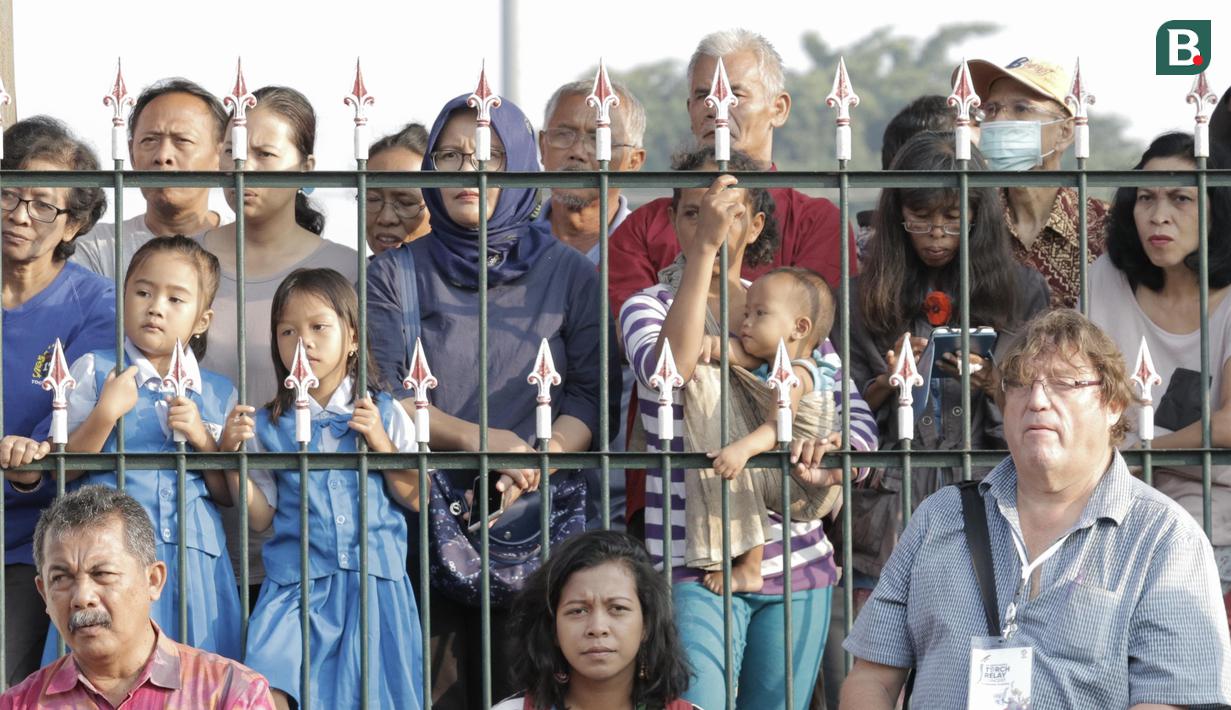 Sejumlah warga menyaksikan kirab obor Asian Games 2018 di Pagelaran Keraton Yogyakarta, Kamis (19/7/2018). Total jarak kirab Obor di Yogya ini sepanjang 11,5 kilometer. (Bola.com/M Iqbal Ichsan)