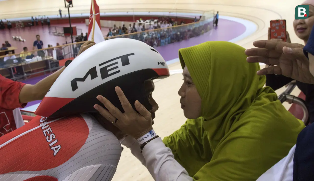 M Fadli pebalap sepeda Indonesia disambut anggota keluarga usai meraih medali emas di nomor 4000 meter Individual Pursuit C4 di Velodrome Rawamangun, Jakarta,  Jumat (11/10/2018).  (Bola.com/Peksi Cahyo)
