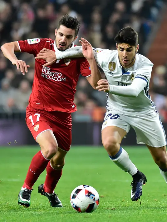 Gelandang Sevilla, Pablo Sarabia (kiri) berebut bola dengan gelandang Real Madrid, Marco Asensio pada pertandingan pertama babak 16 besar Copa del Rey di Santiago Bernabeu, Spanyol (5/1). Madrid menang atas Sevilla 3-0. (AFP Photo/Gerard Julien)