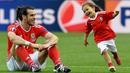 Gareth Bale duduk menyaksikan keceriaan putrinya, Alba Violet usai laga melawan Irlandia Utara pada Piala Eropa 2016 di Parc des Princes, Paris, (25/6/2016). Wales Menang 1-0. (EPA/Georgi Licovski)