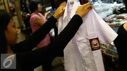 Seorang anak melihat seragam di kawasan Pasar Baru, Jakarta, Selasa (12/7). Menjelang tahun ajaran baru, sejumlah toko penjualan perlengkapan sekolah mulai didatangi warga. (Liputan6.com/Faizal Fanani)
