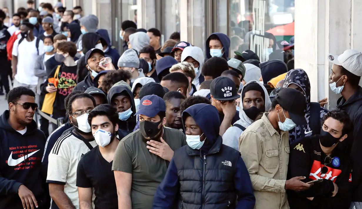 Orang-orang antre untuk memasuki toko Niketown di London, Senin (15/6/2020). Antrean panjang terjadi di luar toko-toko yang berada di sejumlah kota di Inggris saat negara itu melakukan pelonggaran lockdown dan mulai membuka pusat perbelanjaan. (AP/Matt Dunham)