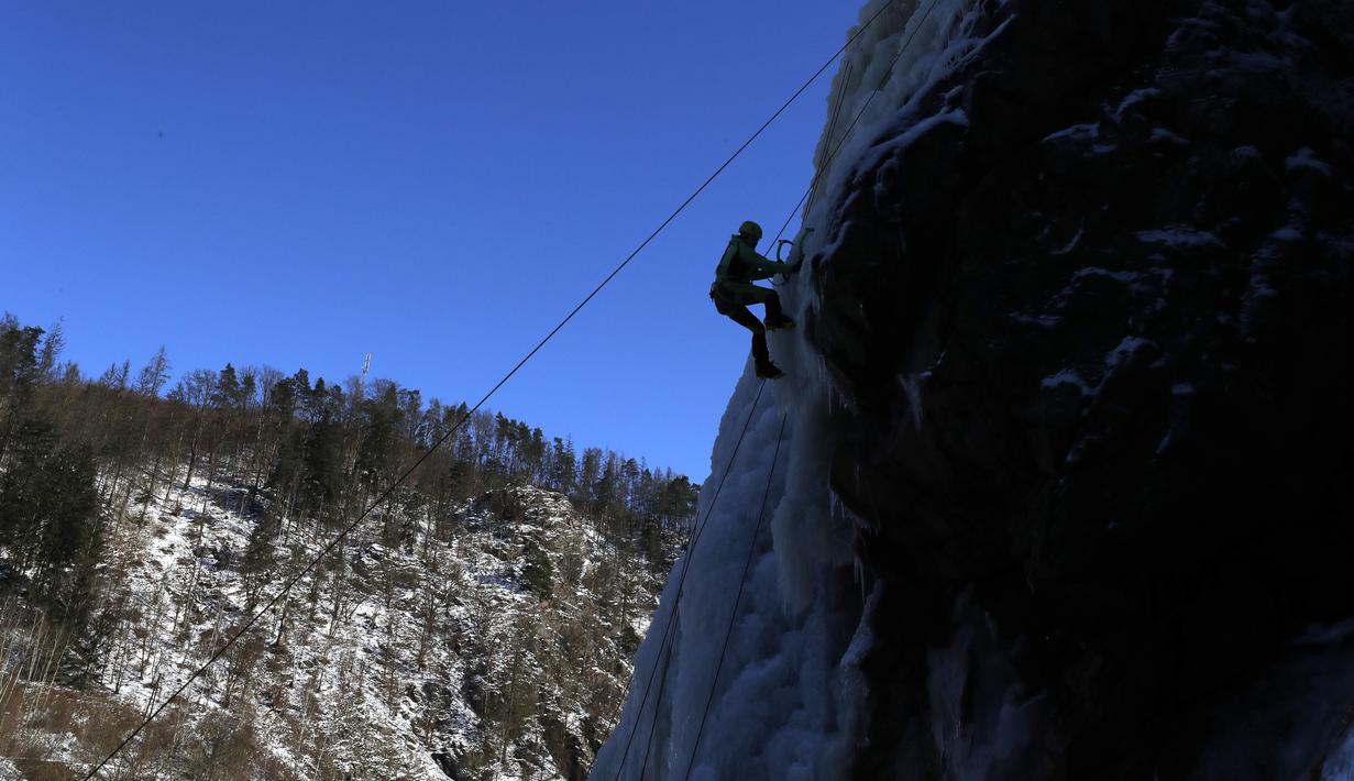 Seorang perempuan memanjat dinding es buatan di desa Vir, Republik Ceko, Minggu (14/2/2021). Ketika suhu turun di Republik Ceko, pemanjat tebing memanfaatkan kondisi beku dengan mengubah permukaan batu menjadi dinding es setinggi 20 meter untuk pendaki. (AP Photo/Petr David Josek)