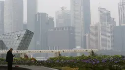 Seorang pria saat berada disamping skyline yang dikelilingi kabut tebal di Singapura (25/9/2015). Sejak Rabu Kualitas udara di Singapura mulai memburuk akibat kabut asap tebal dari wilayah Indonesia. (REUTERS/Edgar Su)