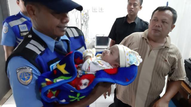 Seorang petugas Avsec menggendong bayi yang ditemukannya di Jalan Perimeter Selatan, Bandara Soetta, Senin (26/11/2018)