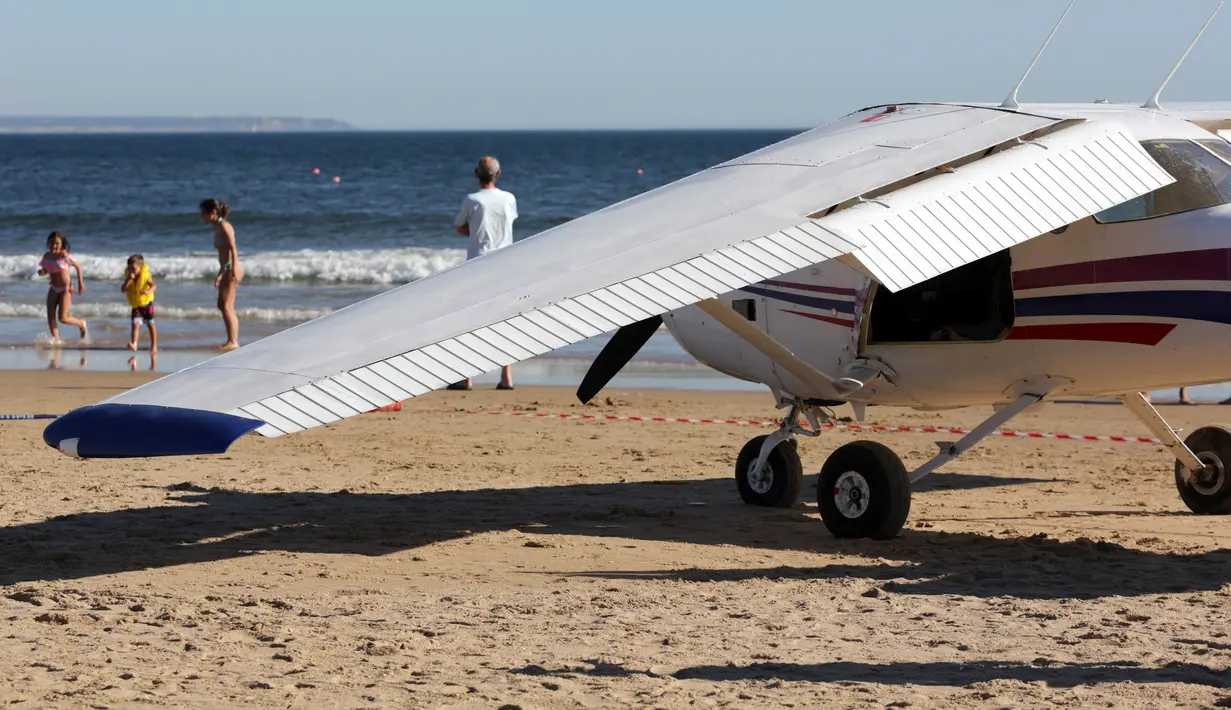 Kondisi sebuah pesawat kecil yang melakukan pendaratan darurat di pantai Sao Joao yang ramai dekat Lisbon, Portugal, Rabu (2/8). Saat mendarat sayap kanan pesawat nampak mengalami kerusakan. (AP Photo/Armando Franca)