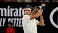 Petenis Swiss, Roger Federer mengembalikan bola ke arah Taylor Fritz dari AS dalam babak 32 besar Australia Terbuka di Melbourne, Jumat (18/1). Federer melaju mulus ke babak 16 besar setelah menang tiga set langsung 6-2 7-5 6-2. (DAVID GRAY/AFP)