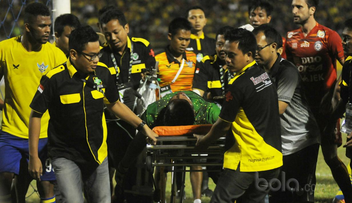 Aji Saka diangkut tim medis setelah menghantam tiang gawang sebelah kanan saat melawan Arema FC pada Liga 1 2017 di Gresik, (12/7/2017). (Bola.com/Iwan Setiawan). 