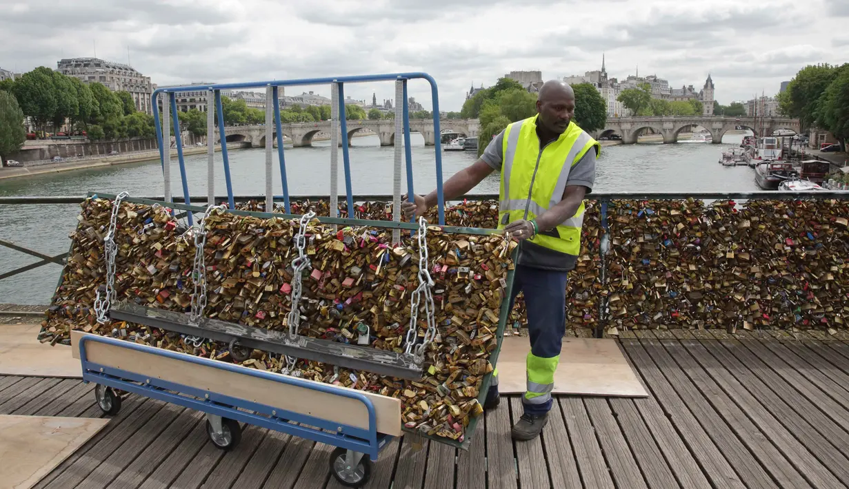 Seorang pekerja memindahkan gembok cinta di Jembatan Pont des Arts di atas Sungai Seine, Paris, Perancis, Senin (1/6/2015). (REUTERS/Philippe Wojazer)