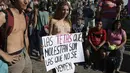 Seorang wanita tanpa penutup dada memegang tulisan bernada protes saat unjuk rasa di Ibu Kota Argentina, Buenos Aires, Selasa (7/1). Aksi protes tersebut juga diramaikan sejumlah pria bertelanjang dada. (AFP PHOTO/Juan MABROMATA)