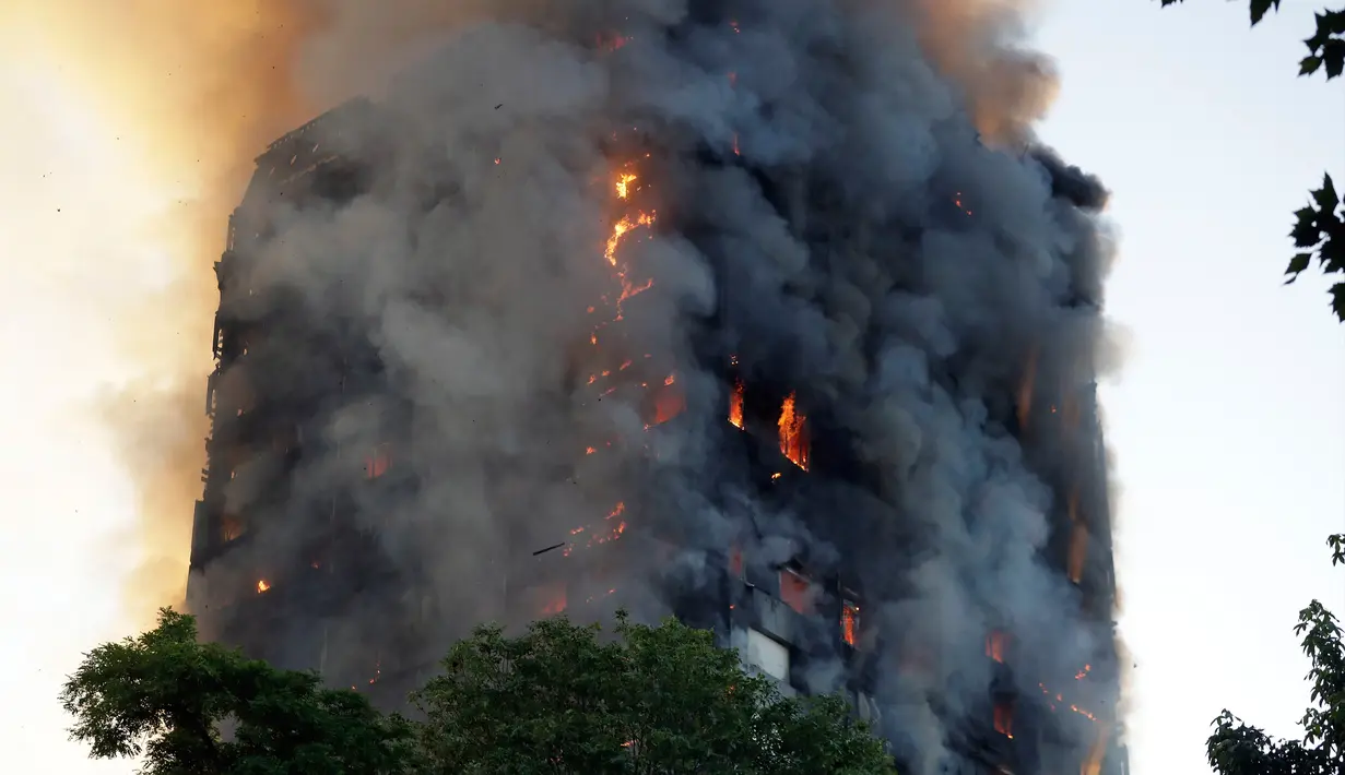 Asap dan api menyelimuti sebuah apartemen bertingkat 27 lantai yang terbakar di London (14/6). Gedung apartemen tersebut terbakar mulai dari lantai dua hingga puncak bangunan. (AP Photo/Matt Dunham)