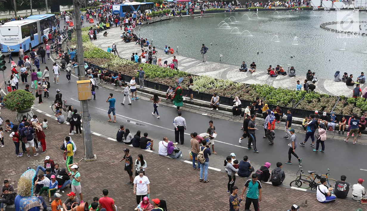 Warga duduk-duduk untuk beristirahat di Jalan Jendral Sudirman dan MH Thamrin ketika pelaksanaan car free day (CFD) di Jakarta, Minggu (11/2). Warga berolahraga atau sekadar berjalan-jalan di hari bebas kendaraan tersebut. (Liputan6.com/Immanuel Antonius)