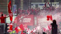 Para pemain Liverpool menyapa fans saat parade juara Liga Champions 2019 di Liverpool, Minggu (2/6). Ribuan fans tumpah ruah di jalanan untuk merayakan keberhasilan pemain membawa pulang trofi Si Kuping Besar ke kota Liverpool. (AP/Richard Sellers)