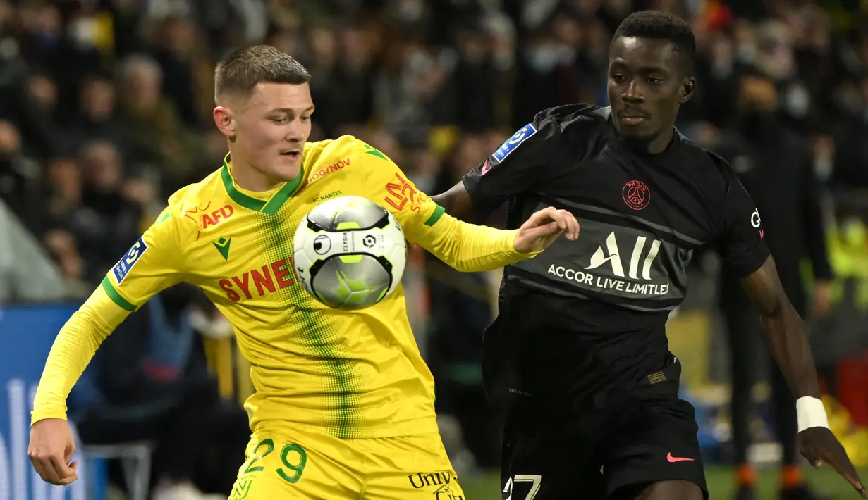 Gelandang Nantes Quentin Merlin Nantes berebut bola dengan gelandang Paris Saint-Germain (PSG) Idrissa Gueye pada laga pekan ke-25 Ligue 1 Prancis di Stade de la Beaujoire, Minggu (20/2/2022) dinihari WIB. PSG keok saat bertandang ke Nantes dengan skor 1-3. (LOIC VENANCE/AFP)