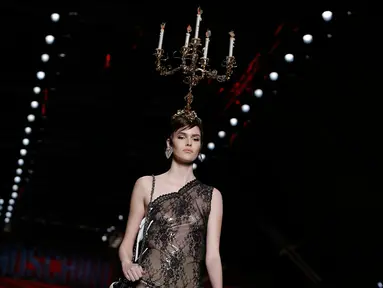 Model mengenakan busana rancangan Moschino dengan hiasan kepala berbentuk tempat lilin dalam Milan Fashion Week Autumn/Winter 2017 di Milan, Italia, (23/2). (AFP Photo / Marco Bertorello)