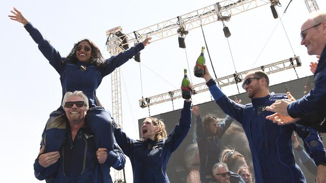 Pendiri Virgin Galactic Sir Richard Branson, dengan Sirisha Bandla di pundaknya, bersorak dengan anggota kru setelah terbang ke luar angkasa dengan pesawat Virgin Galactic pada 11 Juli 2021. Patrick T. FALLON / AFP