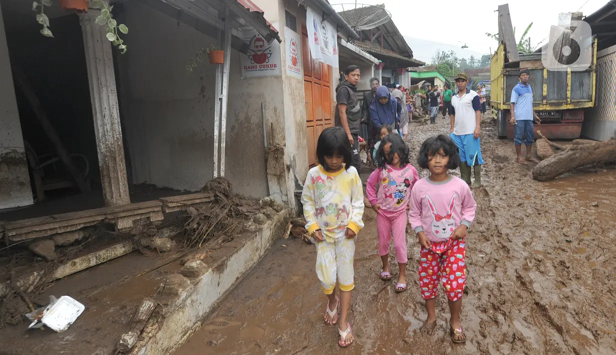 Anak-anak berjalan melintasi lumpur usai banjir bandang melanda Kampung Cibuntu, Desa Pasawahan, Kecamatan Cicurug, Sukabumi, Jawa Barat, Selasa (22/9/2020). Data sementara puluhan bangunan rusak berat, 12 rumah hanyut, dan dua korban hilang masih dicari. (merdeka.com/Arie Basuki)