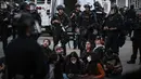 Petugas polisi berdiri di sekitar pengunjuk rasa yang ditangkap setelah demonstrasi menentang operasi imigrasi federal di dekat Balai Kota Los Angeles, Amerika Serikat pada 11 Juni 2025. (RONALDO SCHEMIDT/AFP)