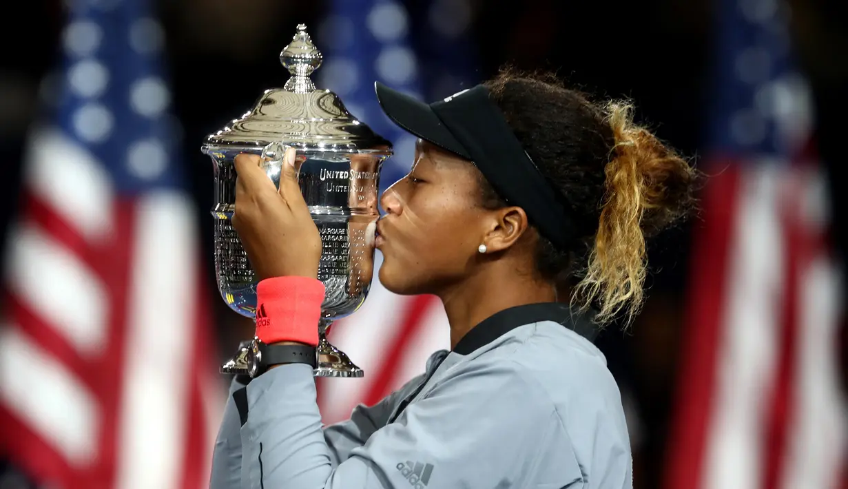 Petenis Jepang, Naomi Osaka mencium trofi turnamen AS Terbuka setelah mengalahkan Serena Williams pada partai final di New York, Sabtu (8/9). Osaka menjadi kampiun AS Terbuka setelah mengalahkan Serena Williams, 6-2, 6-4. (JULIAN FINNEY/GETTY IMAGES/AFP)