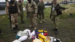 Separatis Pro-Rusia melihat barang-barang milik penumpang MH17 yang berserakan, UKraina, Jumat (18/7/14). (REUTERS/Maxim Zmeyev)