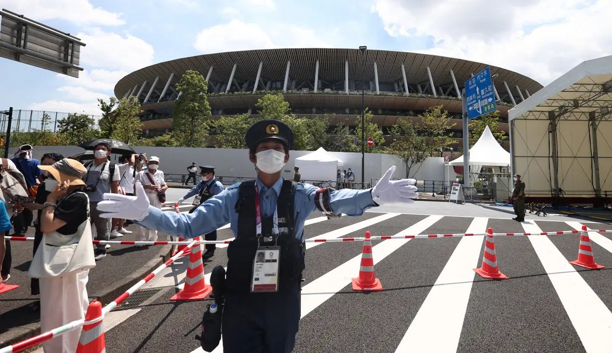 Polisi mengatur kerumunan di luar Stadion Olimpiade sebelum pertunjukan tim aerobatik Angkatan Udara Bela Diri Jepang (JASDF) Blue Impulse jelang upacara pembukaan Olimpiade Tokyo 2020 di Tokyo, Jelang, Jumat (23/7/2021). (Behrouz MEHRI/AFP)