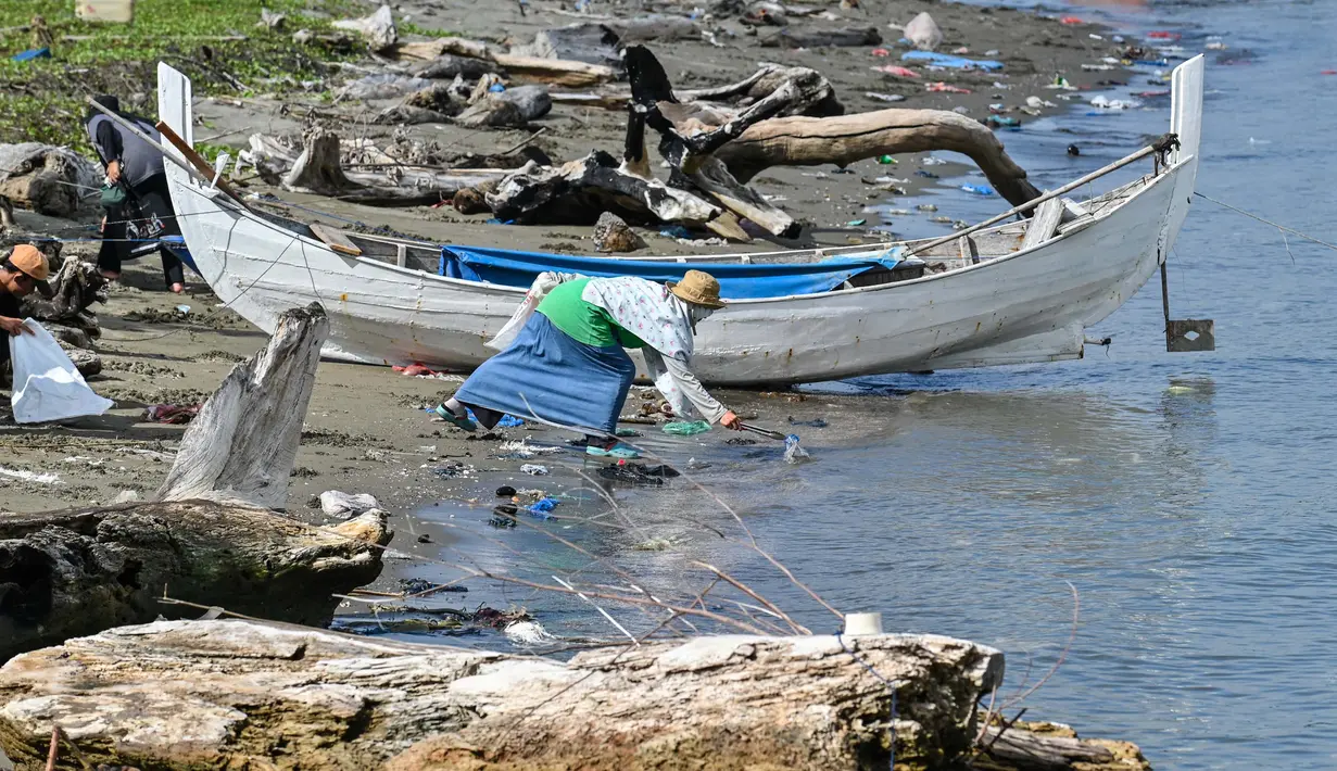 Para duta wisata Agam-Inong (laki-perempuan) membersihkan sampah plastik dan sampah lainnya yang terdampar di pantai selama kampanye di sebuah pantai di Banda Aceh pada 29 Oktober 2023. (CHAIDEER MAHYUDDIN/AFP)
