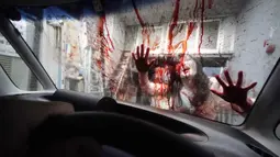 Pemeran zombie tampil dengan darah palsu yang disiramkan ke kaca kendaraan saat demonstrasi pertunjukan rumah hantu drive-in di Tokyo, Jepang, Selasa (18/8/2020). Rumah hantu drive-in ini diadakan di tengah pandemi COVID-19. (AP Photo/Eugene Hoshiko)