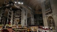 Ketika Misa Malam Natal berakhir, Paus, yang didorong dengan kursi roda, turun ke basilika dengan patung Bayi Yesus seukuran manusia di pangkuannya dan diapit oleh anak-anak yang membawa karangan bunga. Patung itu ditempatkan di palungan di kandang Natal di basilika. (AP Photo/Gregorio Borgia)