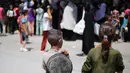 Anak-anak Palestina menyaksikan orang-orang mengantre untuk mendapatkan makanan hangat yang dibagikan oleh dapur amal di kamp pengungsi Nuseirat, Jalur Gaza tengah pada 15 Juli 2025. (Eyad BABA/AFP)