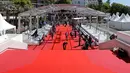 Pekerja memasang karpet merah di depan pintu masuk utama jelang upacara pembukaan Festival Film Cannes 2019 di Cannes, Prancis, Selasa (14/5/2019). Bila biasanya karpet merah berisi bintang film ternama, kali ini para bintang pop dan rock yang akan hilir mudik. (REUTERS/Stephane Mahe)