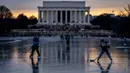 Lincoln Memorial terlihat saat bersaudara Jacek Zavora (21) dan Zach Zavora (10) dari Arlington bermain hoki di Reflecting Pool atau Kolam Refleksi yang membeku, National Mall, Washington, Amerika Serikat, 26 Desember 2022. Layanan Taman Nasional sebelumnya mengatakan peraturan taman tidak mengizinkan seluncur es di kolam karena membahayakan. (AP Photo/Andrew Harnik)