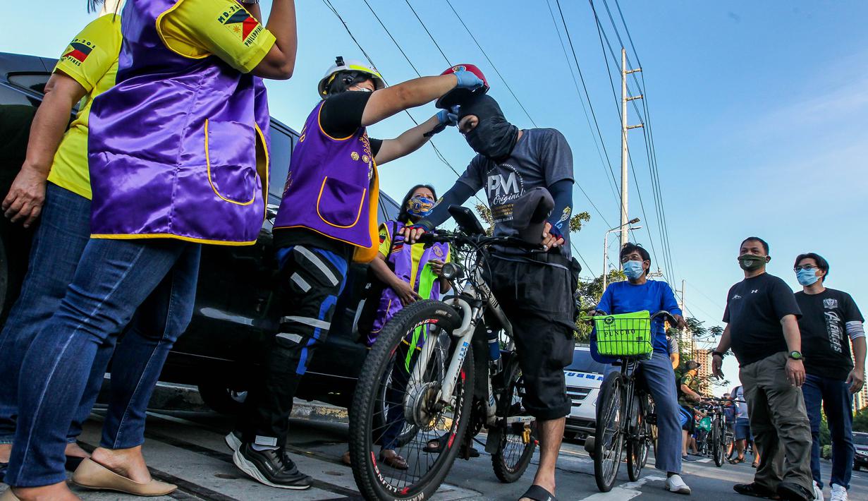 Seorang anggota lembaga swadaya masyarakat membagikan helm dan selempang reflektif secara gratis kepada pengendara sepeda di Manila, Filipina (9/7/2020). (Xinhua/Rouelle Umali)