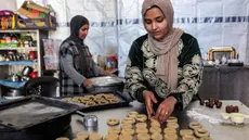 Para wanita menyiapkan biskuit tradisional "kaak" yang berbentuk cincin menjelang Idul Fitri, hari raya yang menandai berakhirnya bulan puasa suci Ramadan, di Kota Gaza pada 16 Maret 2026. (Omar AL-QATTAA/AFP)