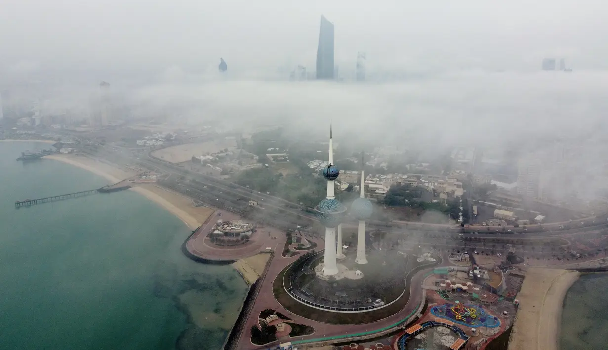 Foto udara ini memperlihatkan Kuwait Towers ketika pagi berkabut di Kota Kuwait terlihat dalam foto udara, Selasa (14/3/2023). Kemunculan kabut memperlihatkan pemandangan indah, dimana kota Kuwait terlihat seperti negeri di atas awan. (Photo by Yasser Al-Zayyat / AFP)