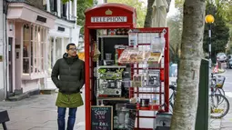 Umar Khalid berpose di luar kotak telepon merah tempat dia mengelola kedai kopi di Hampstead Heath, London Utara (20/12). Kotak telepon umum merah klasik di Inggris ini dialihfungsikan untuk berbagai jenis kegunaan baru. (AFP Photo/Tolga Akmen)