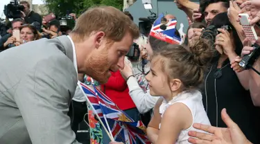 Pangeran Harry menyapa seorang bocah pemberi selamat di luar Kastil Windsor, Inggris, Jumat (18/5). Pangeran Harry dan Meghan Markle akan menikah pada 19 Mei 2018. (Ben Birchall/PA via AP)