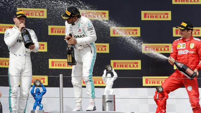 Pebalap Mercedes Lewis Hamilton (tengah) disemprot sampanye oleh pebalap Ferrari Charles Leclerc (kanan) disaksikan pebalap Mercedes Valtteri Bottas saat menjuarai F1 GP Prancis 2019 di Sirkuit Paul Ricard, Minggu (23/6/2019). (AP Photo/Claude Paris)