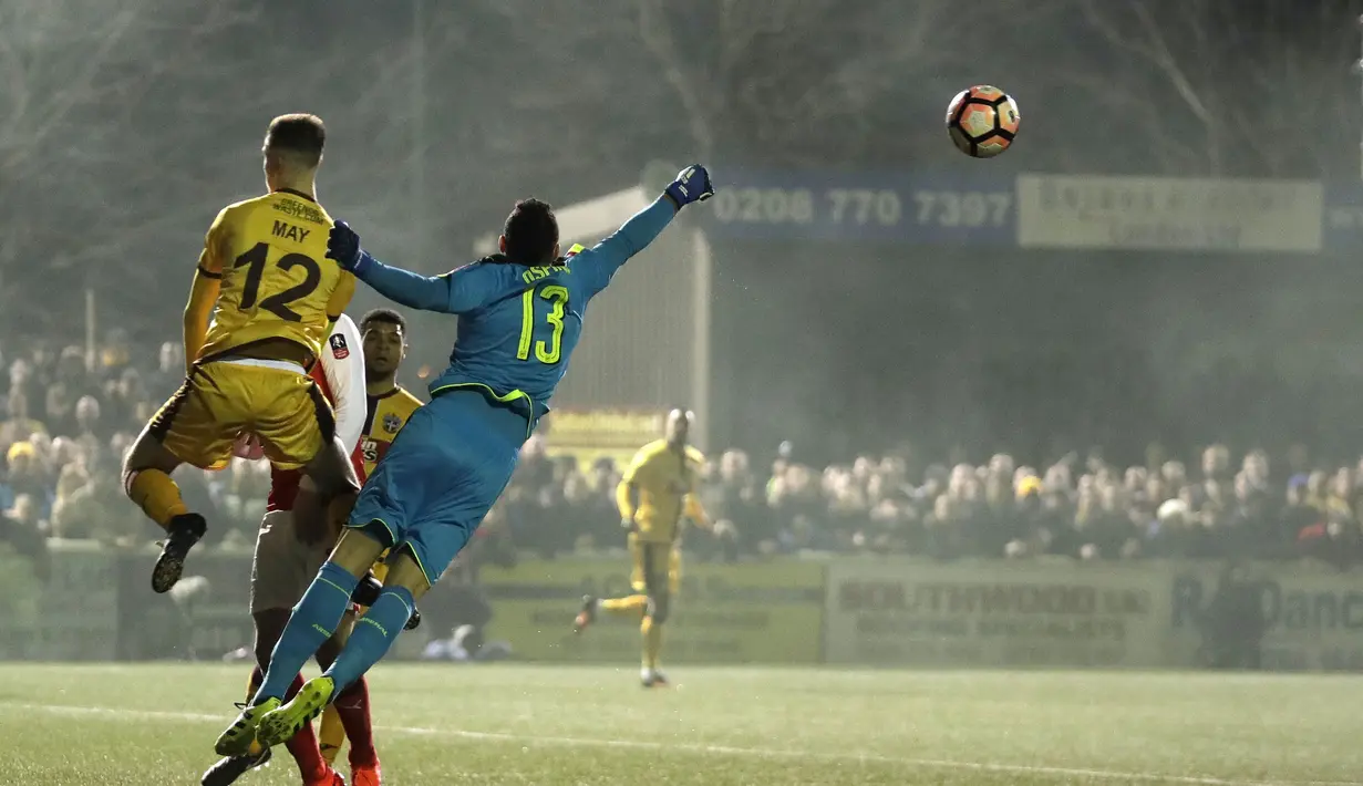 Aksi kiper Arsenal, David Ospina menghalau bola dari kejaran pemain Sutton United, Adam May pada putaran kelima Piala FA di Gander Green Lane stadium, London, (20/2/2017). Arsenal menang 2-0. (AP/Matt Dunham)