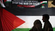 Para pengunjuk rasa pro-Palestina berdiri di depan bendera dan spanduk besar dalam unjuk rasa yang diadakan untuk menandai peringatan "Nakba" atau "Malapetaka" tahun 1948, di Sydney pada tanggal 15 Mei 2024. (DAVID GRAY/AFP)