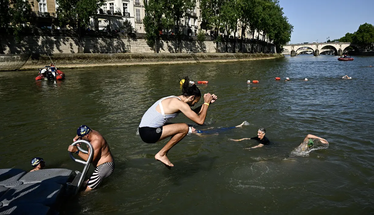 Setelah para pejabat meninggalkan tepi Sungai Seine, banyak perenang masih berada di air, beberapa bermain bola dan lainnya berlatih loncat dari kolam buatan. (JULIEN DE ROSA / AFP)