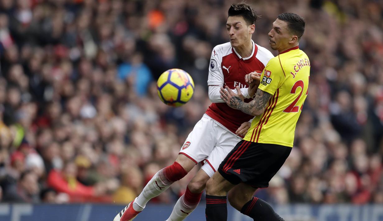 Gelandang Arsenal, Mesut Ozil, berebut bola dengan bek Watford, Jose Holebas, pada laga Preimer League di Stadion Emirates, Minggu (11/3/2018). Arsenal menang 3-0 atas Watford. (AP/Matt Dunham)
