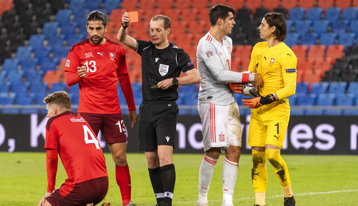 Wasit memberikan kartu merah kepada pemain Swiss, Nico Elvedi, saat melawan Spanyol pada laga UEFA Nations League di Stadion St. Jakob-Park, Minggu (15/11/2020). Kedua tim bermain imbang 1-1. (Alessandro della Valle/Keystone via AP)