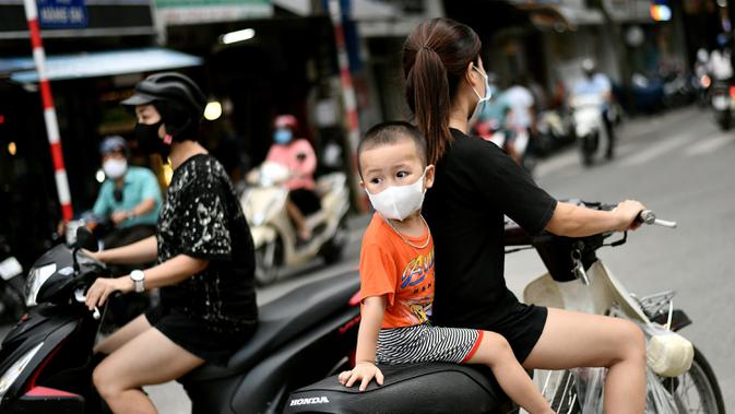 Anak laki-laki melihat ke belakang saat mengendarai skuter dengan seorang perempuan di Hanoi, ibu kota Vietnam pada 11 Agustus 2020. Setelah mencatat nol kasus COVID-19 selama lebih dari tiga bulan, Vietnam melaporkan sejumlah infeksi baru di dalam negeri sejak akhir Juli. (MANAN VATSYAYANA/AFP)