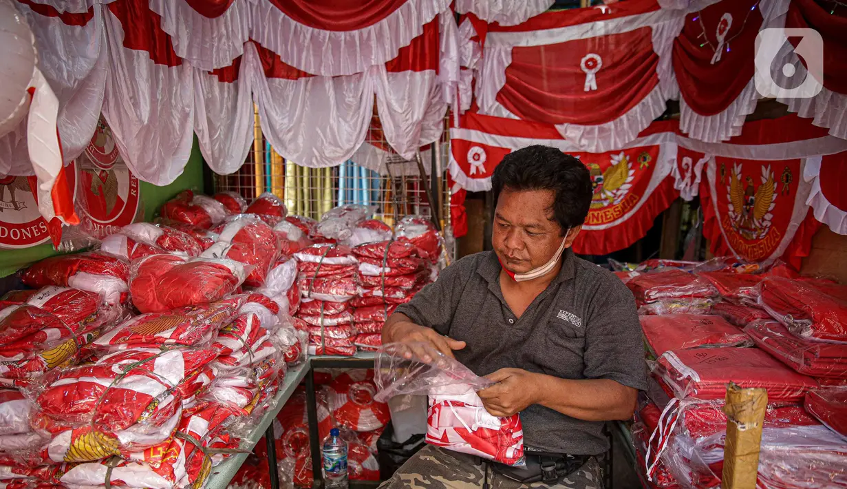 Pedagang merapikan pernak pernik HUT Republik Indonesia di Pasar Jatinegara, Jakarta, Selasa (10/8/2021). Dua tahun pandemi Covid-19 berjalan, penjual pernak pernik hingga bendera merah putih  turun 50-70 persen serta daya beli masyarakat pun turun karena PPKM Darurat. (Liputan6.com/Faizal Fanani)